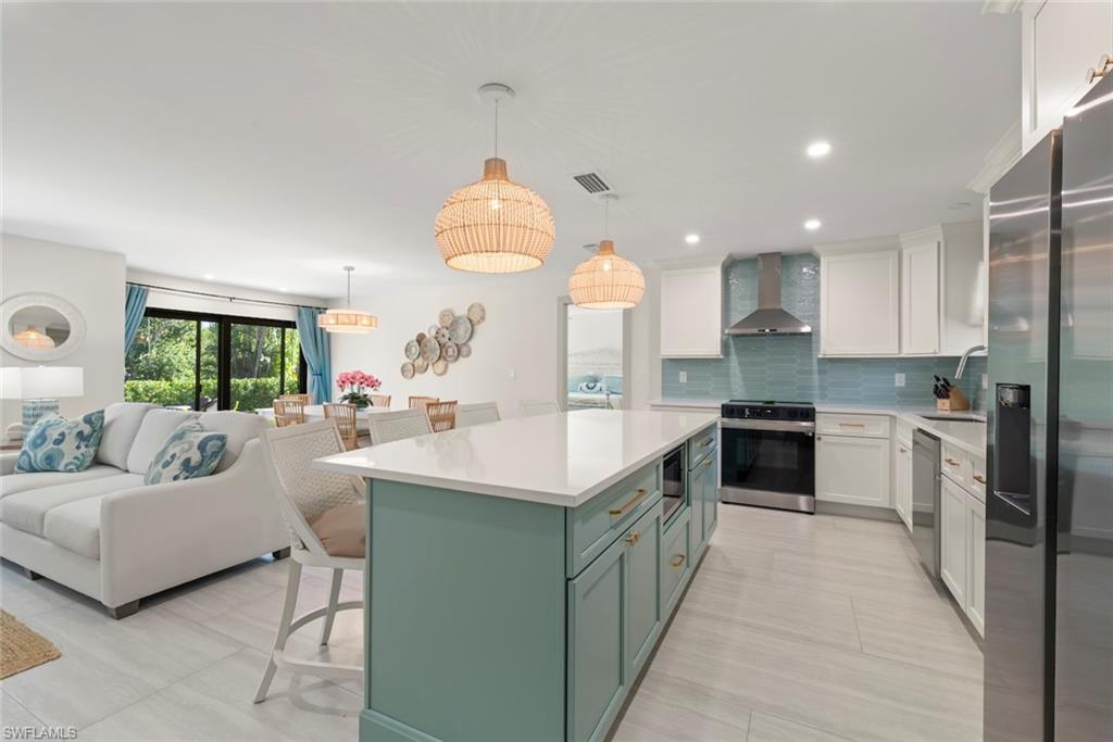 Kitchen featuring a kitchen bar, white cabinetry, appliances with stainless steel finishes, green cabinetry, and recessed lighting