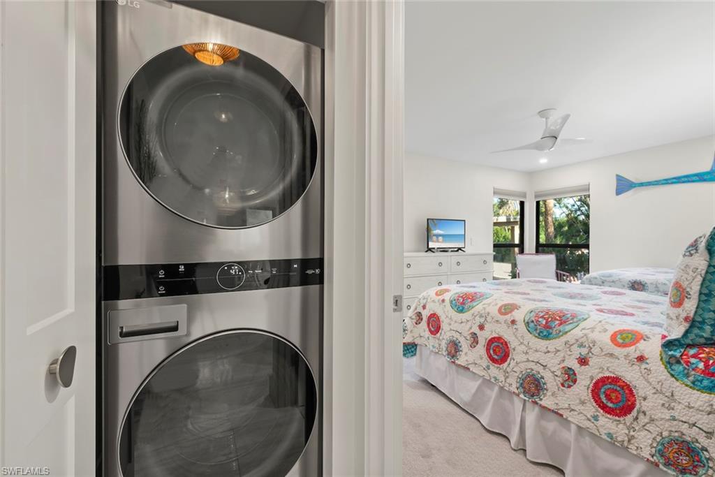 Laundry room with light carpet, stacked washer / dryer, and a ceiling fan