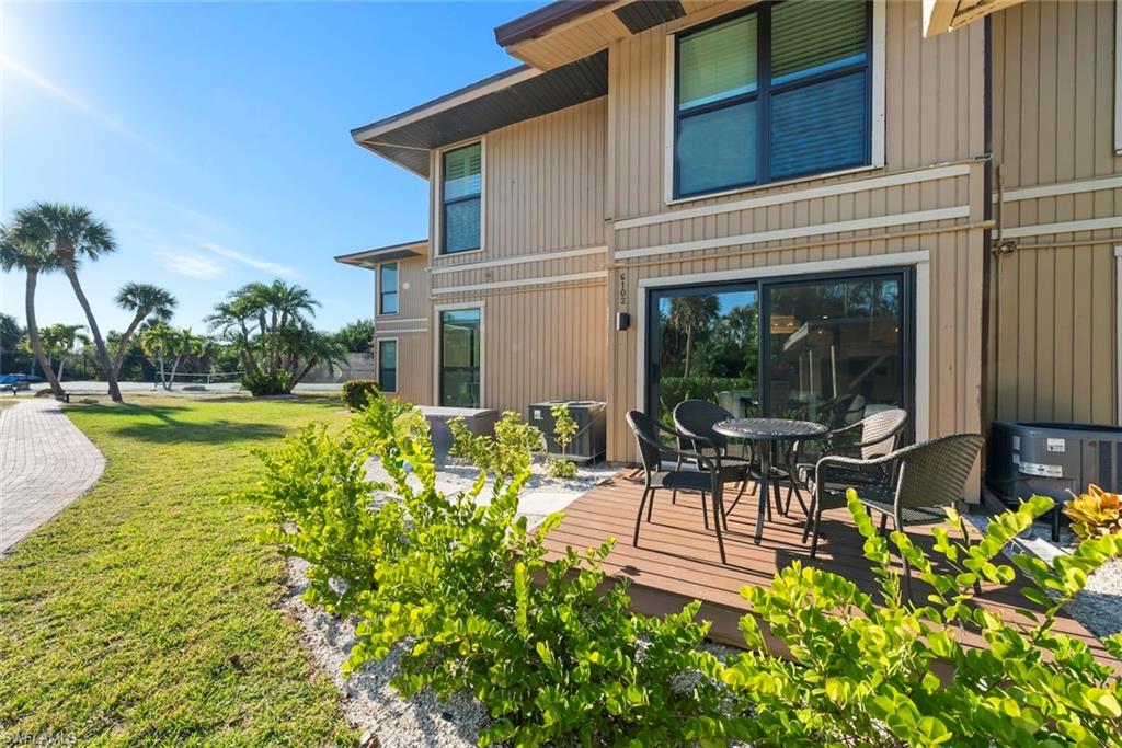 Rear view of property featuring a yard, a wooden deck, and outdoor dining area