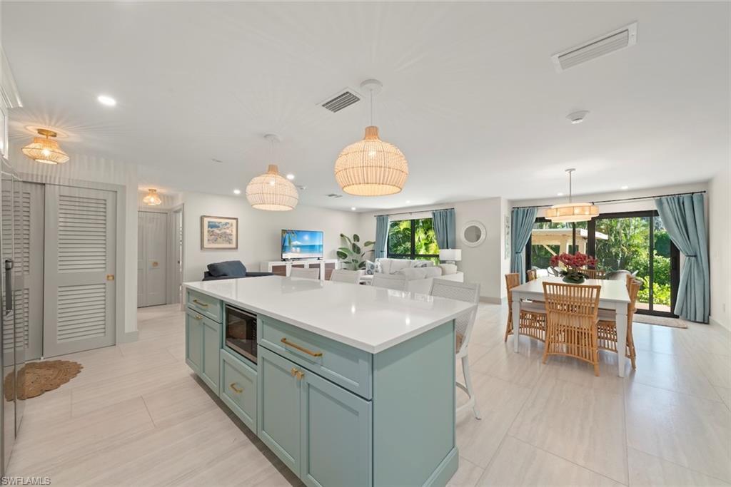 Kitchen featuring open floor plan, a kitchen bar, a center island, pendant lighting, and black microwave