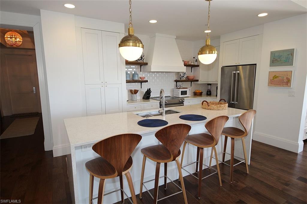 Kitchen featuring a kitchen bar, pendant lighting, white cabinetry, custom range hood, and recessed lighting