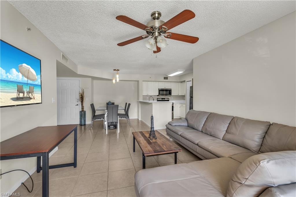 Living area featuring light tile patterned floors, a textured ceiling, and ceiling fan