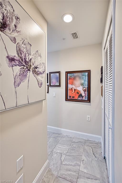 Hallway featuring baseboards and light marble finish flooring