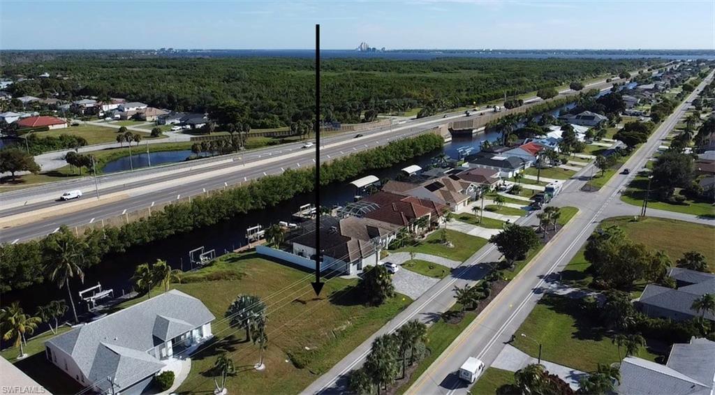 Aerial perspective of suburban area featuring a highway and a large body of water