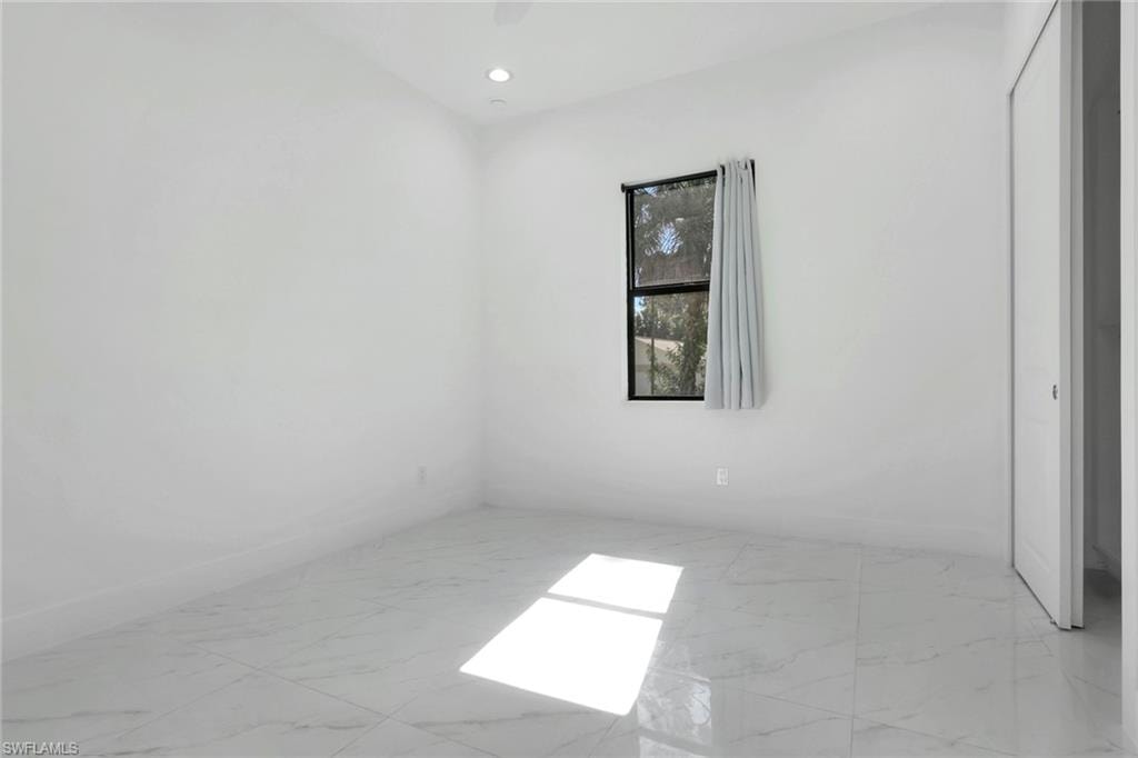 Empty room featuring light marble finish flooring and recessed lighting