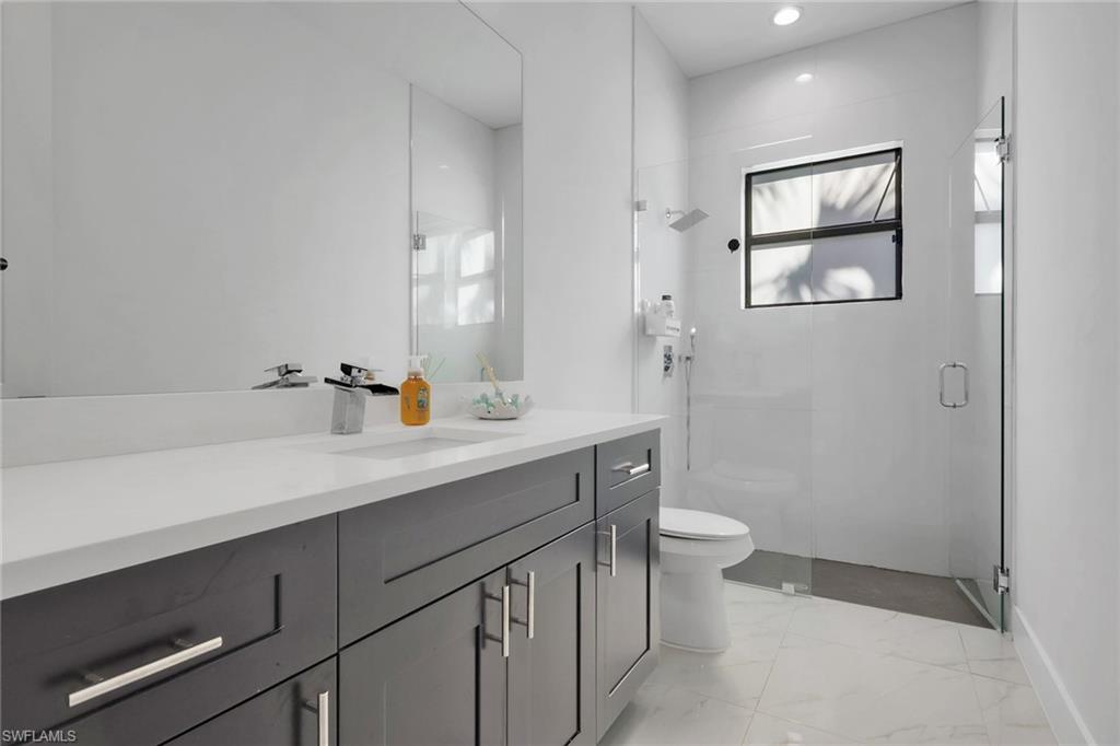 Full bath with vanity, a stall shower, light marble finish flooring, and recessed lighting
