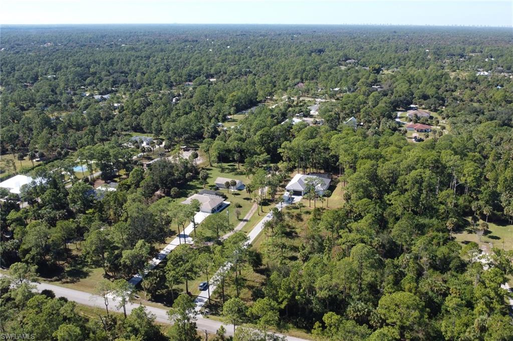 Aerial view of property and surrounding area with a forest