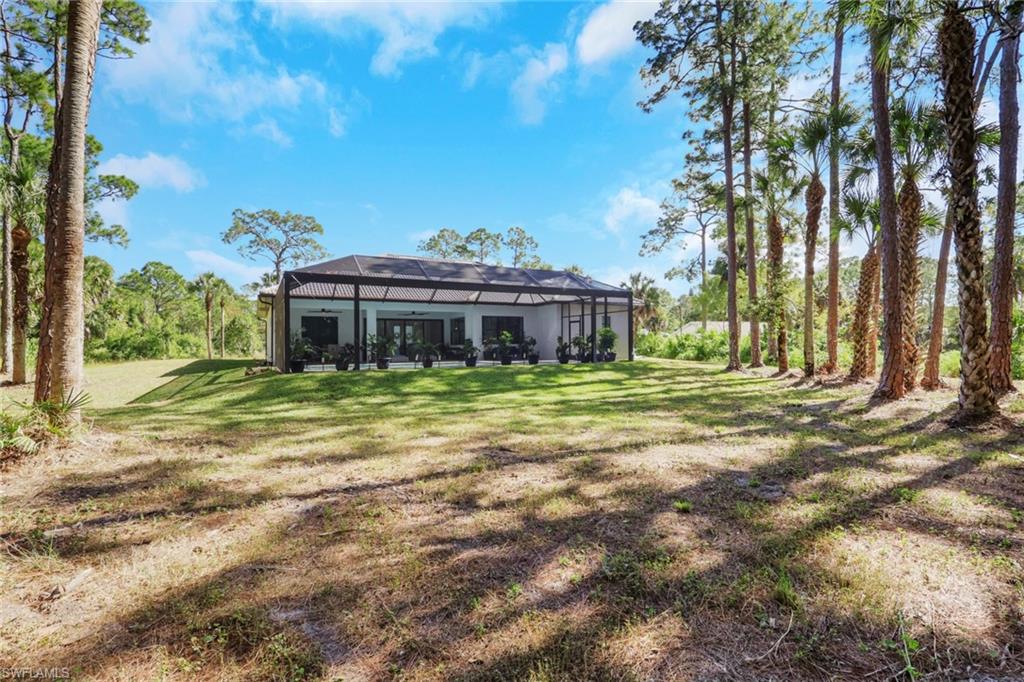 Back of property with glass enclosure, a sunroom, and a yard