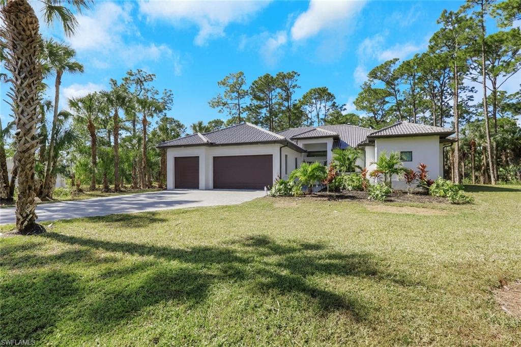 View of front of house featuring a front lawn, stucco siding, an attached garage, and driveway