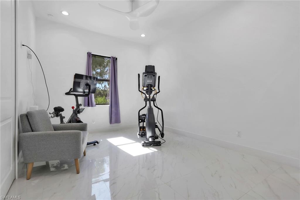Workout area with light marble finish floors and recessed lighting