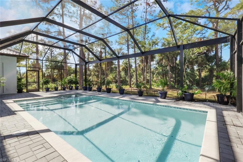Swimming pool featuring a lanai, a sunroom, and a patio
