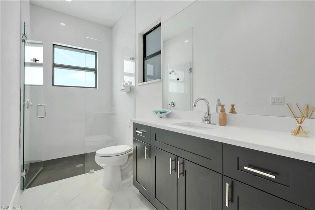 Bathroom featuring vanity, a shower stall, light marble finish floors, and recessed lighting