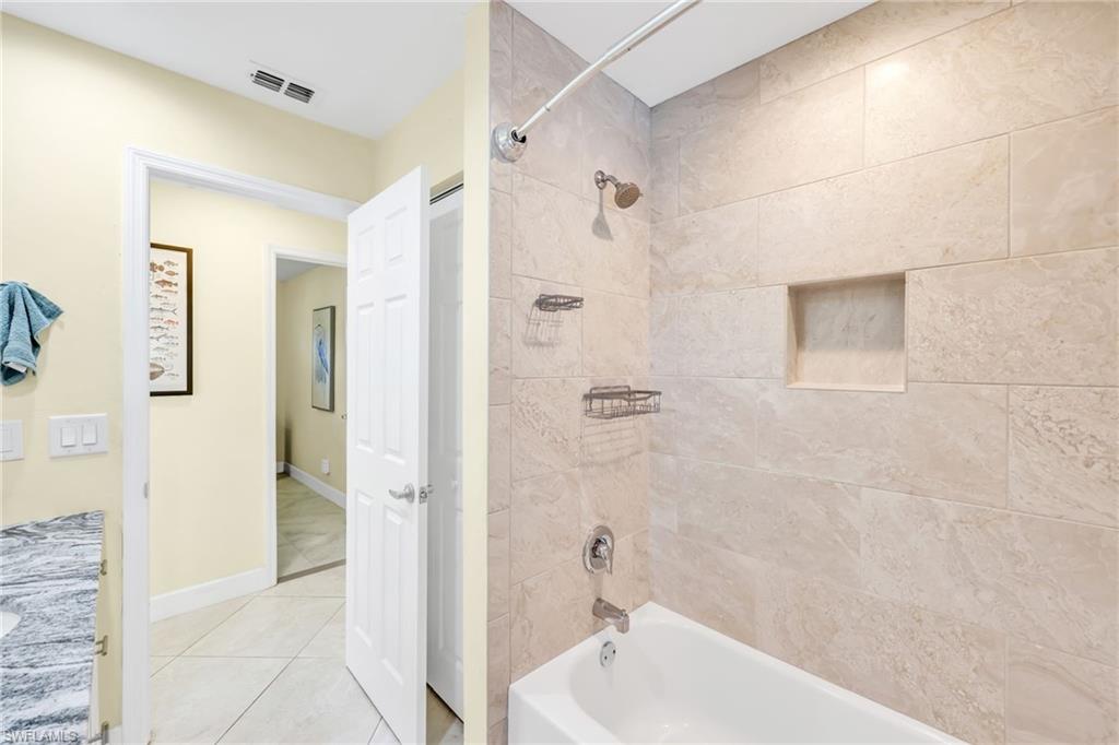 Bathroom with shower / washtub combination, vanity, and tile patterned flooring