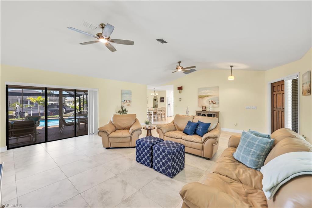 Living room featuring lofted ceiling, ceiling fan, and tile patterned floors