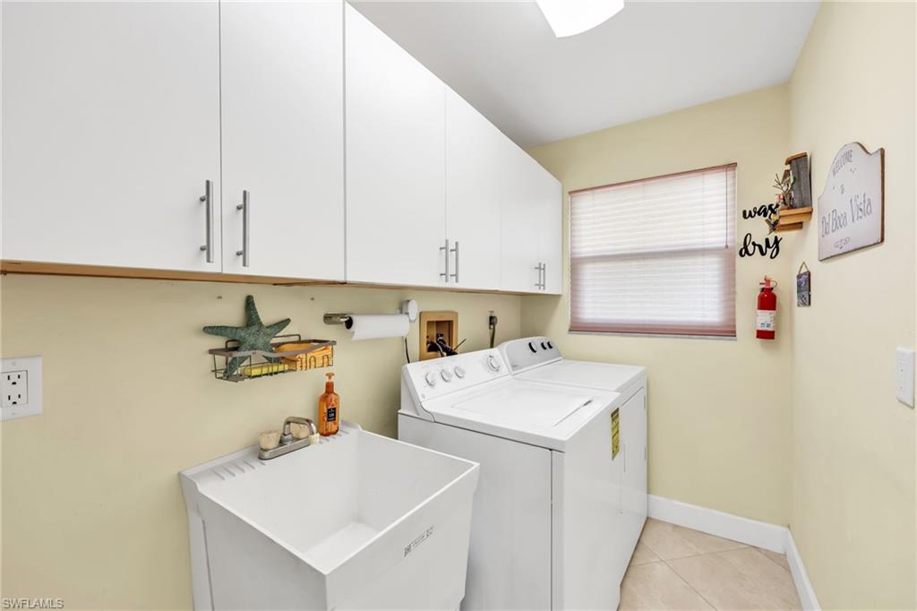 Laundry room with cabinet space, washer and dryer, and light tile patterned floors