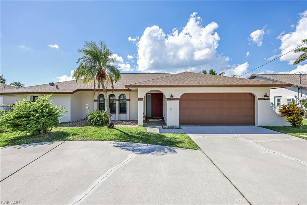 View of front of home featuring stucco siding, driveway, a front yard, and a garage