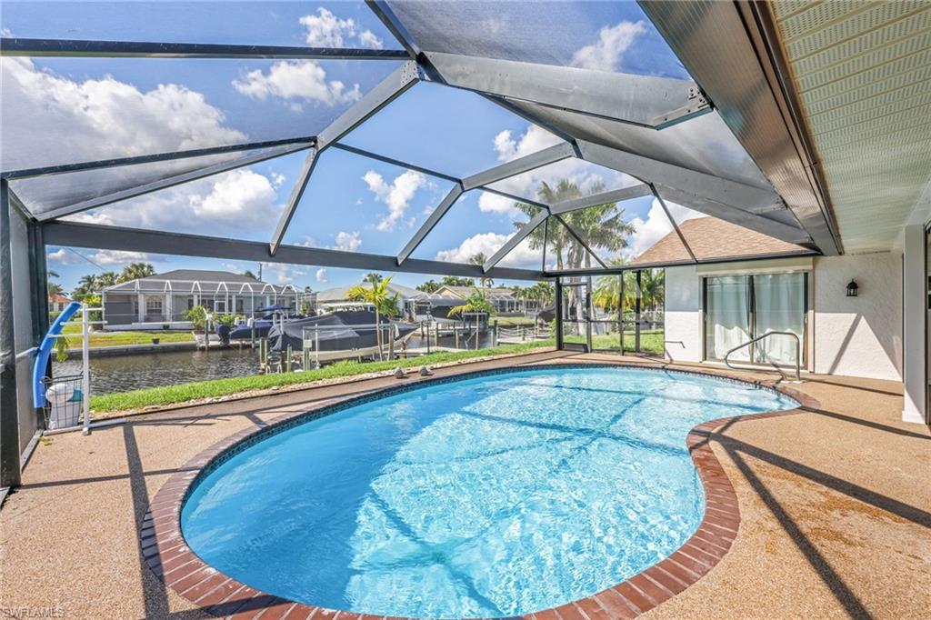 Swimming pool with a sunroom, glass enclosure, a patio area, and a water view