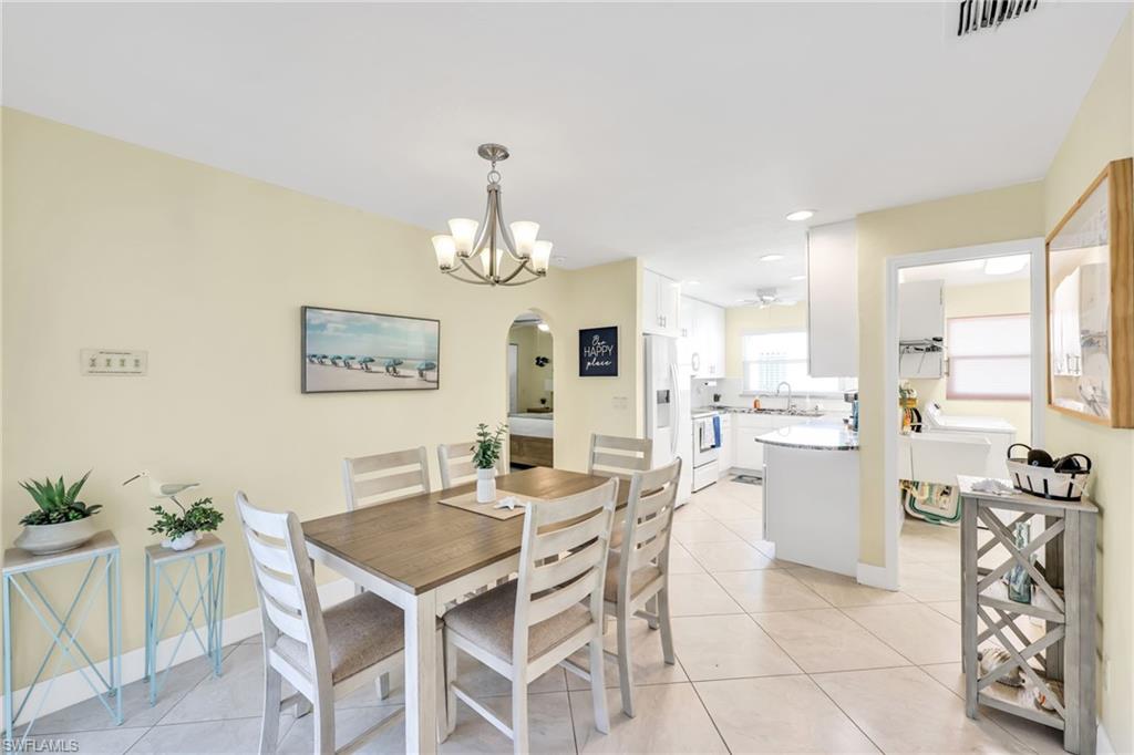 Dining area featuring light tile patterned floors, arched walkways, a chandelier, and recessed lighting