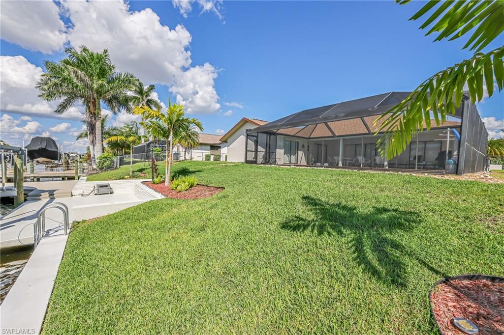 View of grassy yard featuring a lanai, a sunroom, and a patio