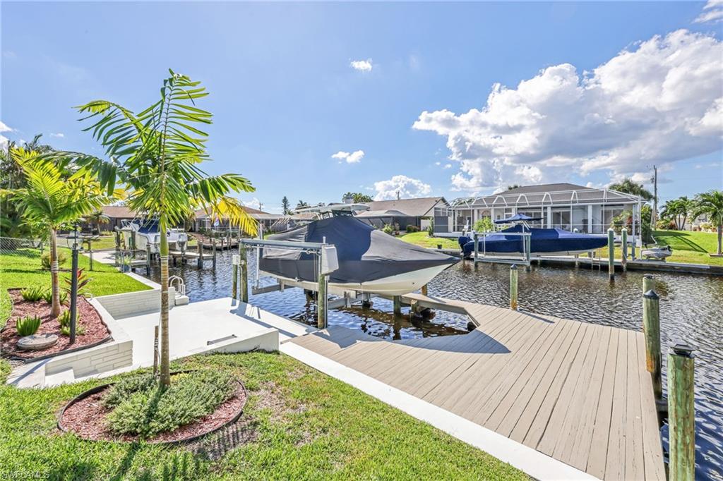 Dock area featuring boat lift, a water view, and a lawn