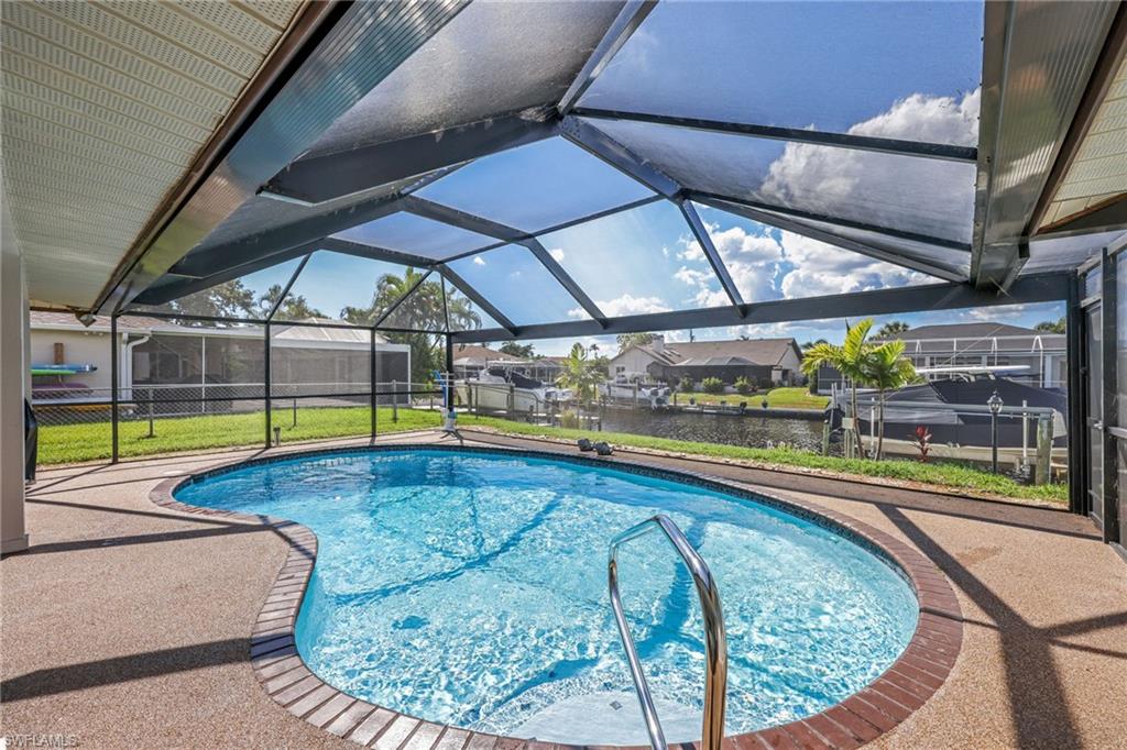 Outdoor pool featuring a sunroom, glass enclosure, a patio, and a yard
