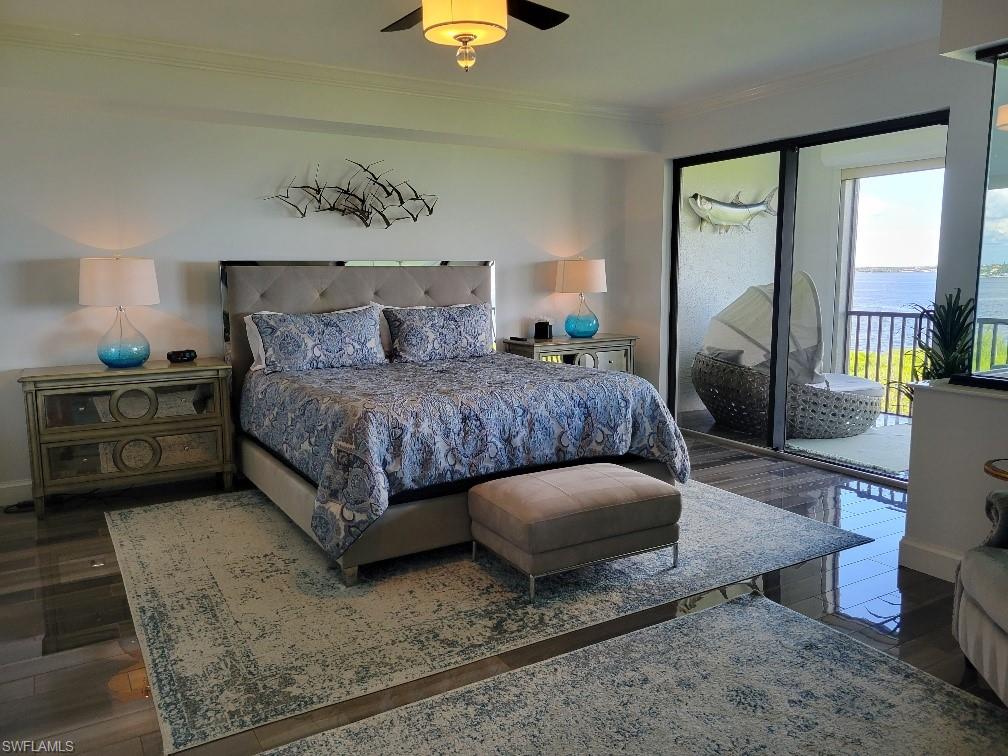 Bedroom featuring access to outside, a water view, dark wood-style flooring, ornamental molding, and a ceiling fan