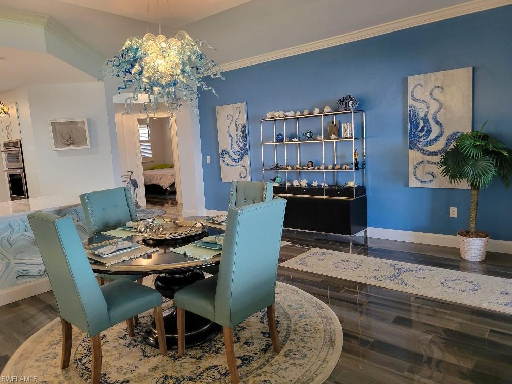 Dining area with ornamental molding, dark wood-type flooring, and a chandelier