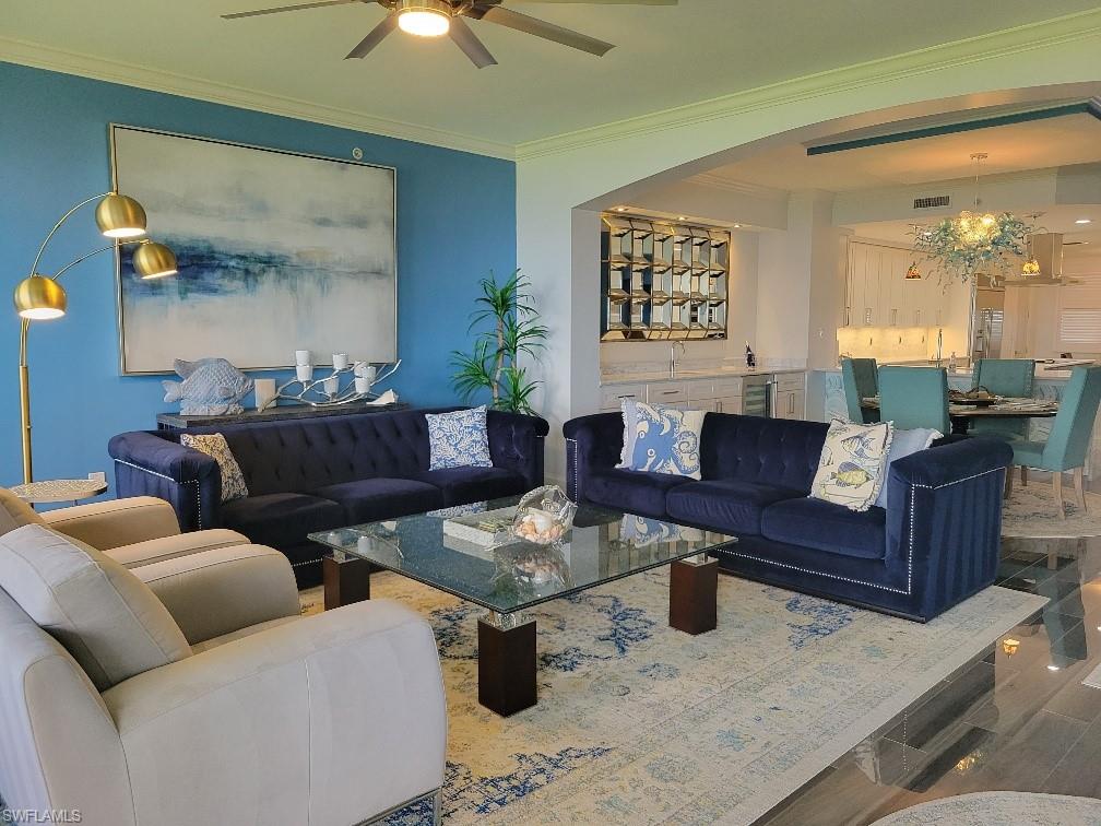 Living room featuring crown molding, wood finished floors, ceiling fan, and beverage cooler
