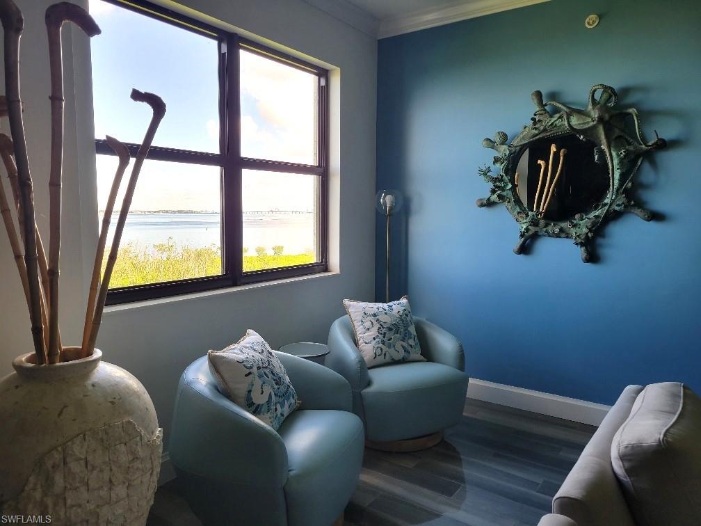 Living area with a water view, wood finished floors, and crown molding