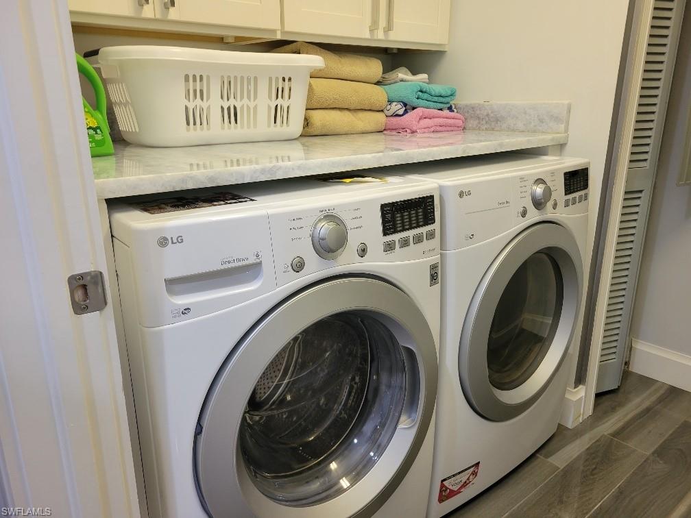 Laundry room with cabinet space, washer and dryer, and wood tiled floors