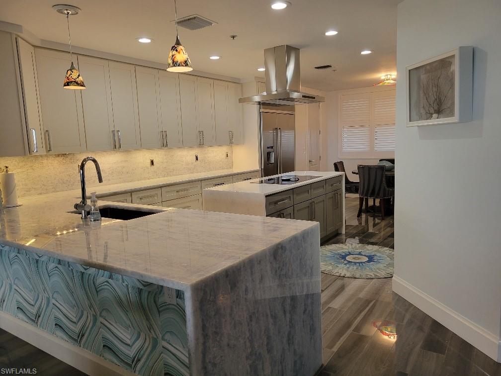Kitchen featuring light stone counters, hanging light fixtures, dark wood finished floors, recessed lighting, and tasteful backsplash
