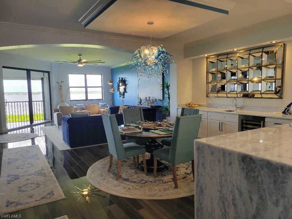 Dining area with crown molding, ceiling fan, dark wood-style floors, and beverage cooler