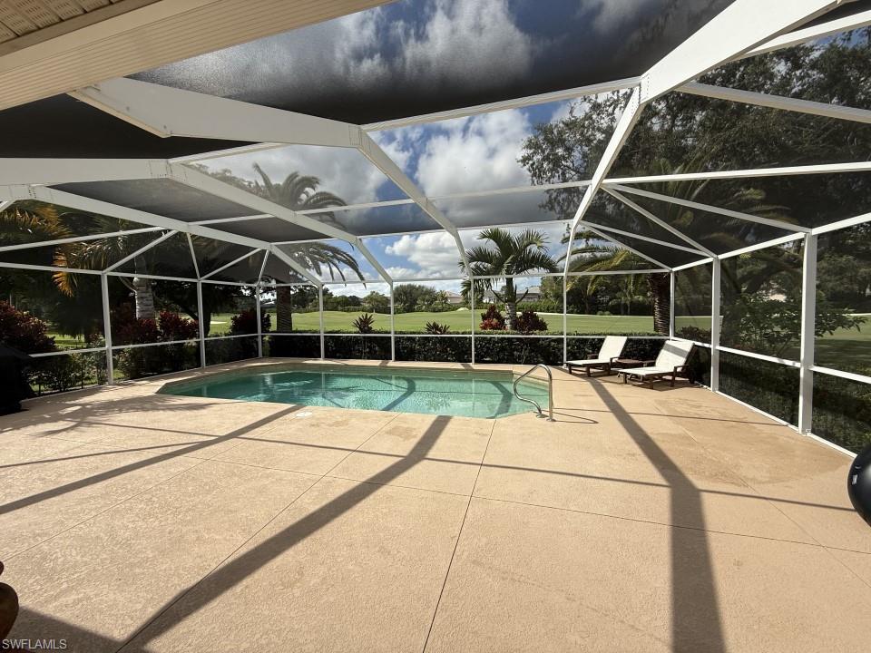 Outdoor pool with a patio area, a sunroom, and glass enclosure