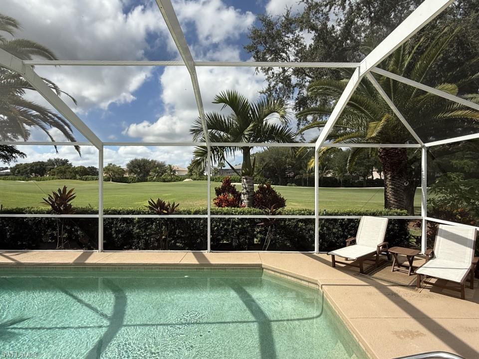 Swimming pool featuring a sunroom, glass enclosure, and view of golf course