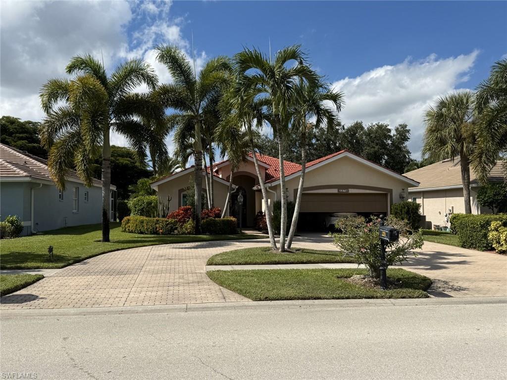 View of front of home featuring decorative driveway, stucco siding, and a front lawn