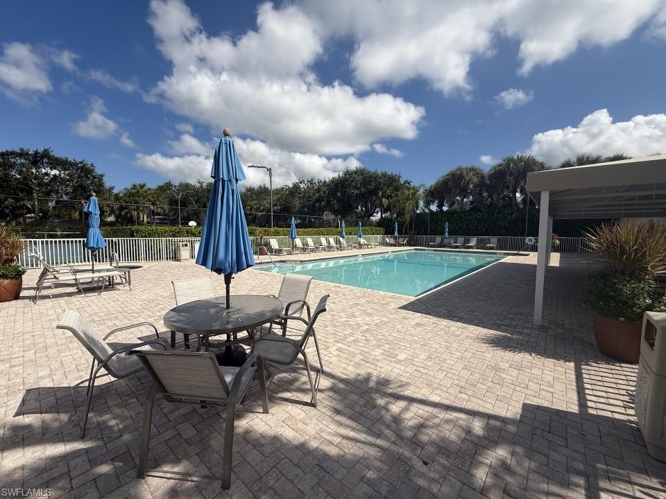 Community pool with a patio area and view of scattered trees