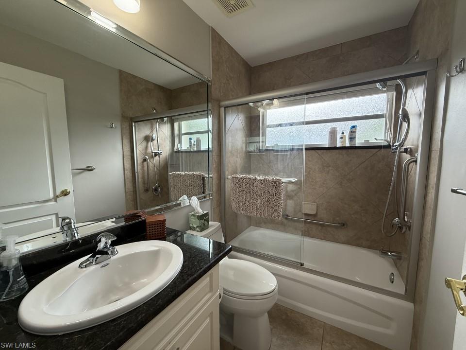 Guest Bathroom featuring vanity, enclosed tub / shower combo, and tile patterned flooring