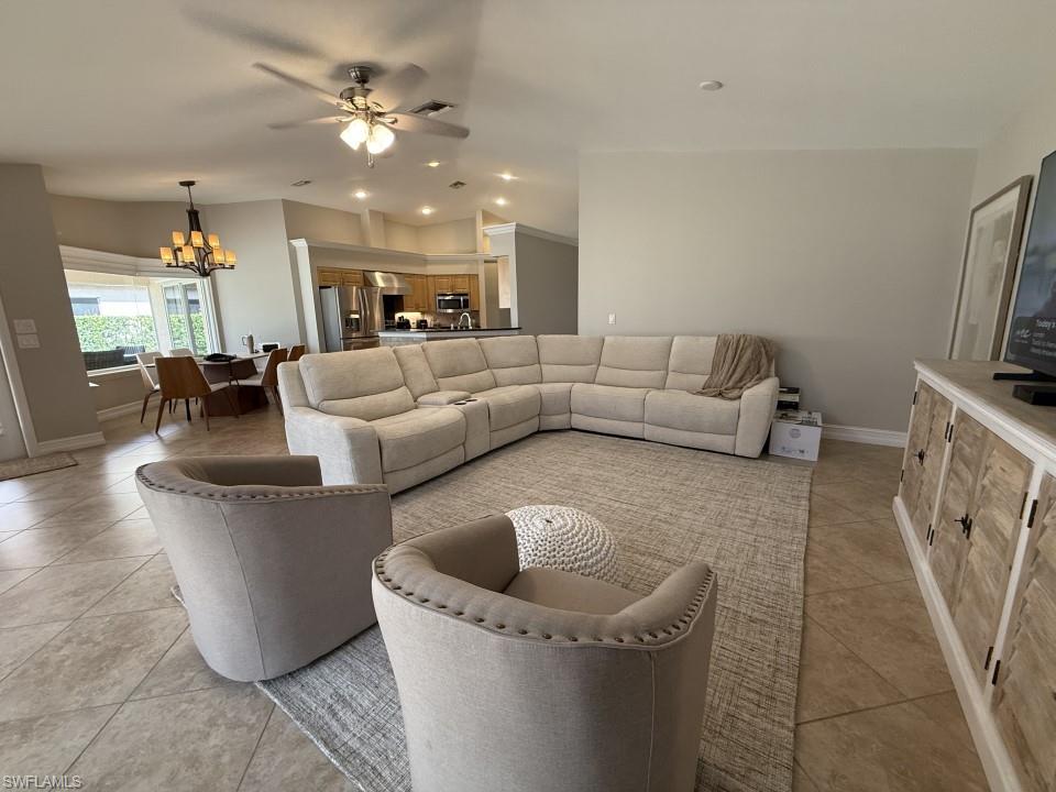 Living room with a chandelier, recessed lighting, a ceiling fan, light tile patterned flooring, and lofted ceiling