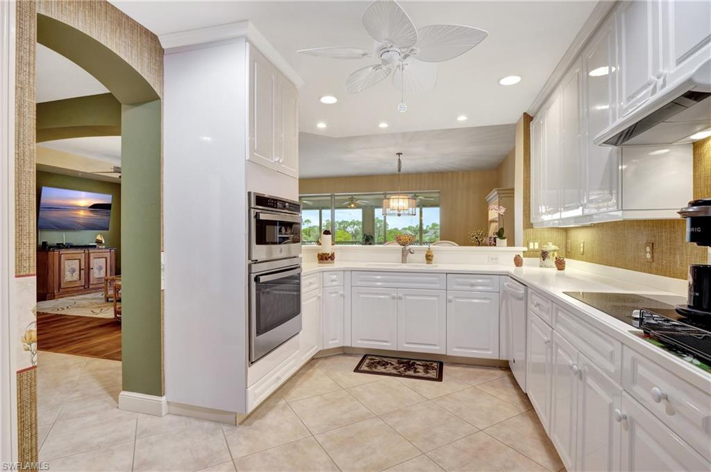 Kitchen with a ceiling fan, white cabinetry, arched walkways, decorative light fixtures, and recessed lighting