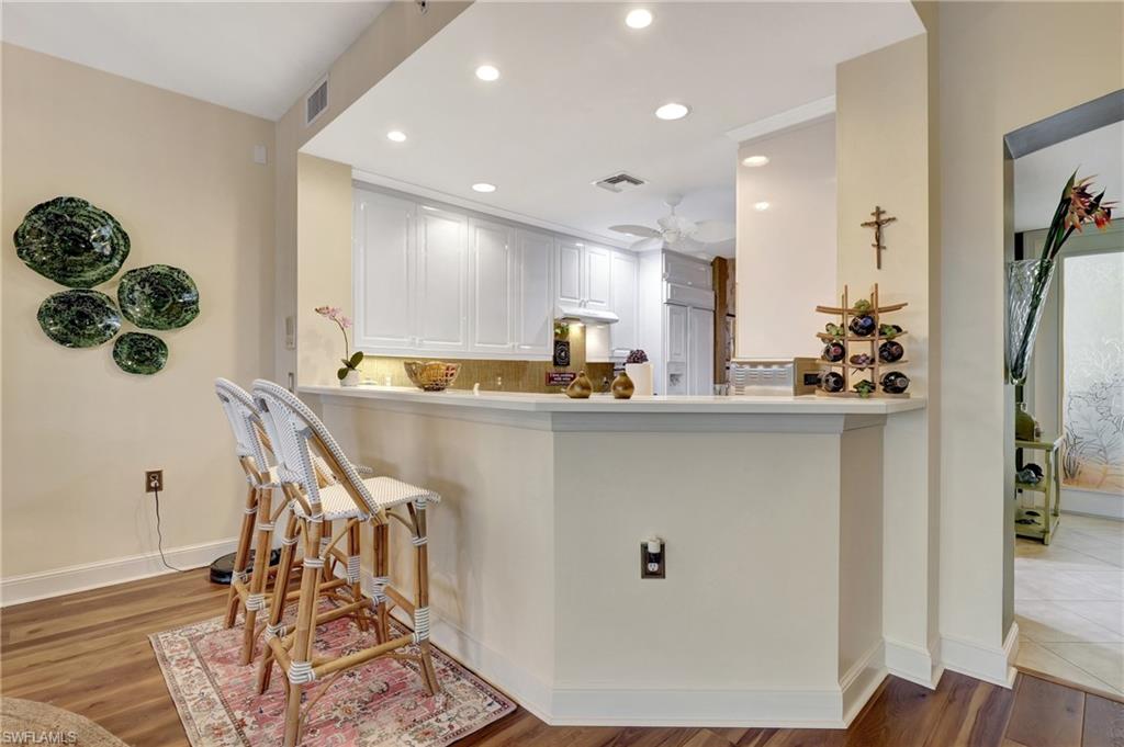 Kitchen with light wood finished floors, recessed lighting, white cabinets, a breakfast bar area, and backsplash