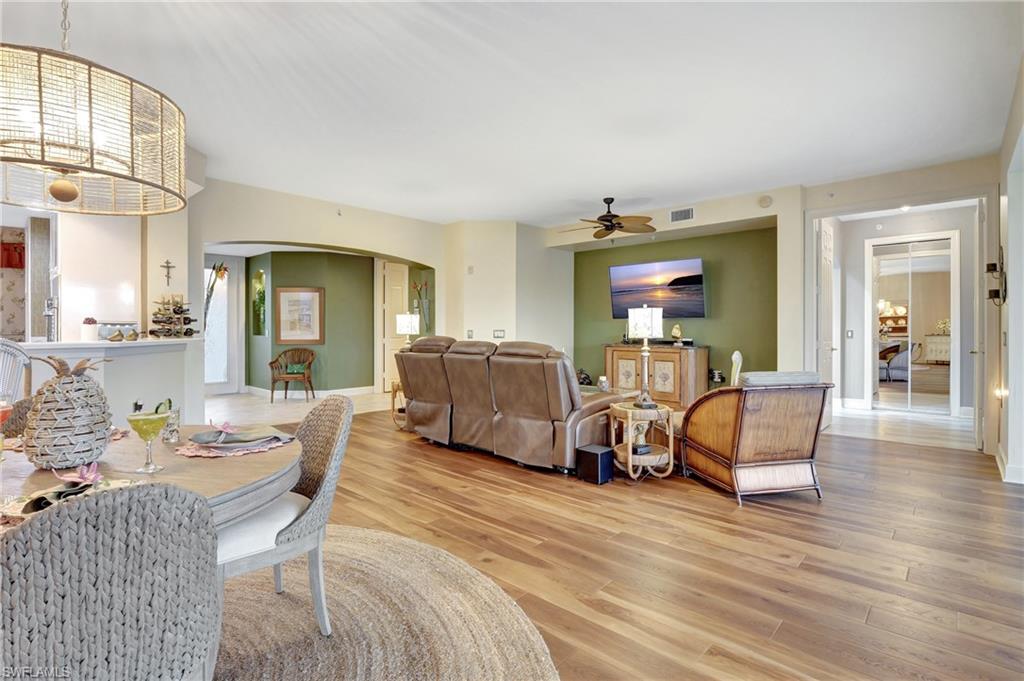 Dining space featuring arched walkways, light wood finished floors, and a ceiling fan