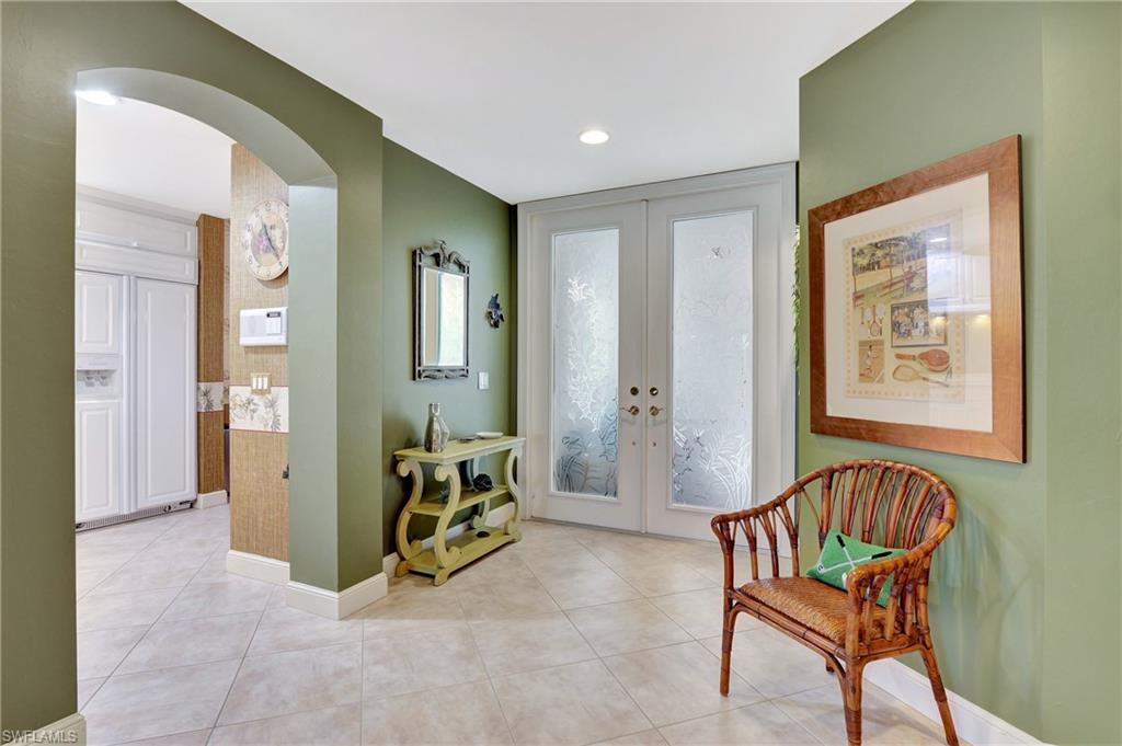Foyer entrance with light tile patterned floors, french doors, arched walkways, and recessed lighting