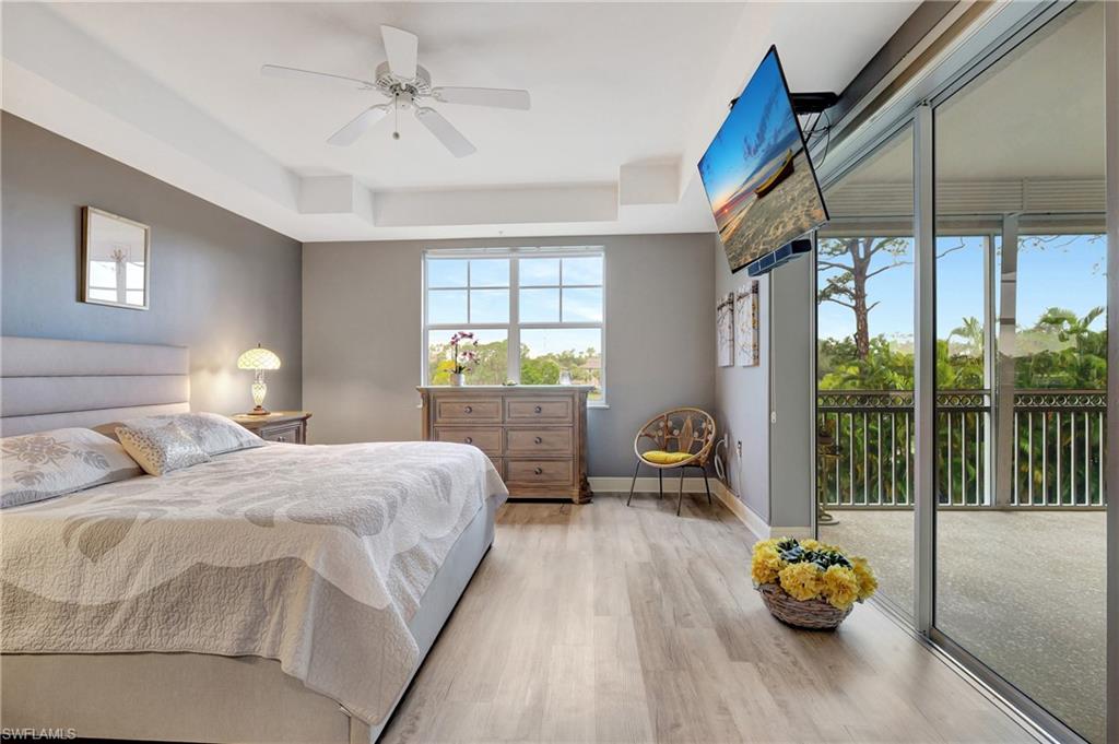 Bedroom with a raised ceiling, light wood-style flooring, access to outside, and ceiling fan