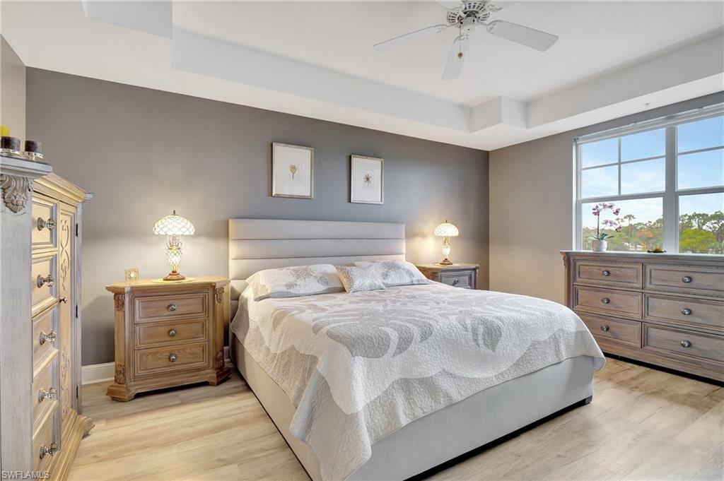 Bedroom featuring light wood-style floors, a tray ceiling, and a ceiling fan