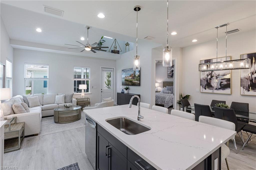 Kitchen with ceiling fan, sink, light hardwood / wood-style flooring, and a kitchen island with sink