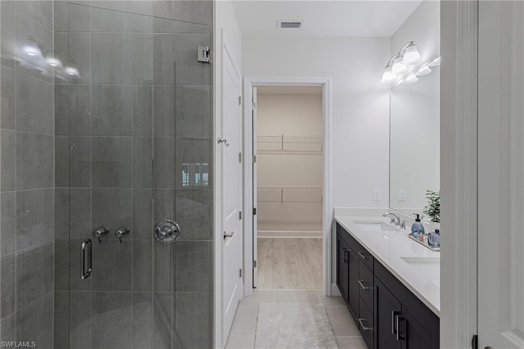Bathroom featuring dual vanity, a shower with door, and wood-type flooring