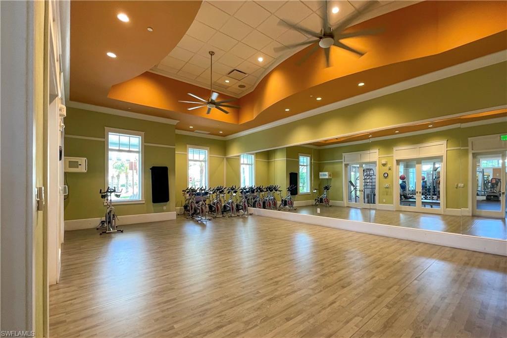 Workout area with hardwood / wood-style flooring, a raised ceiling, a high ceiling, and ceiling fan
