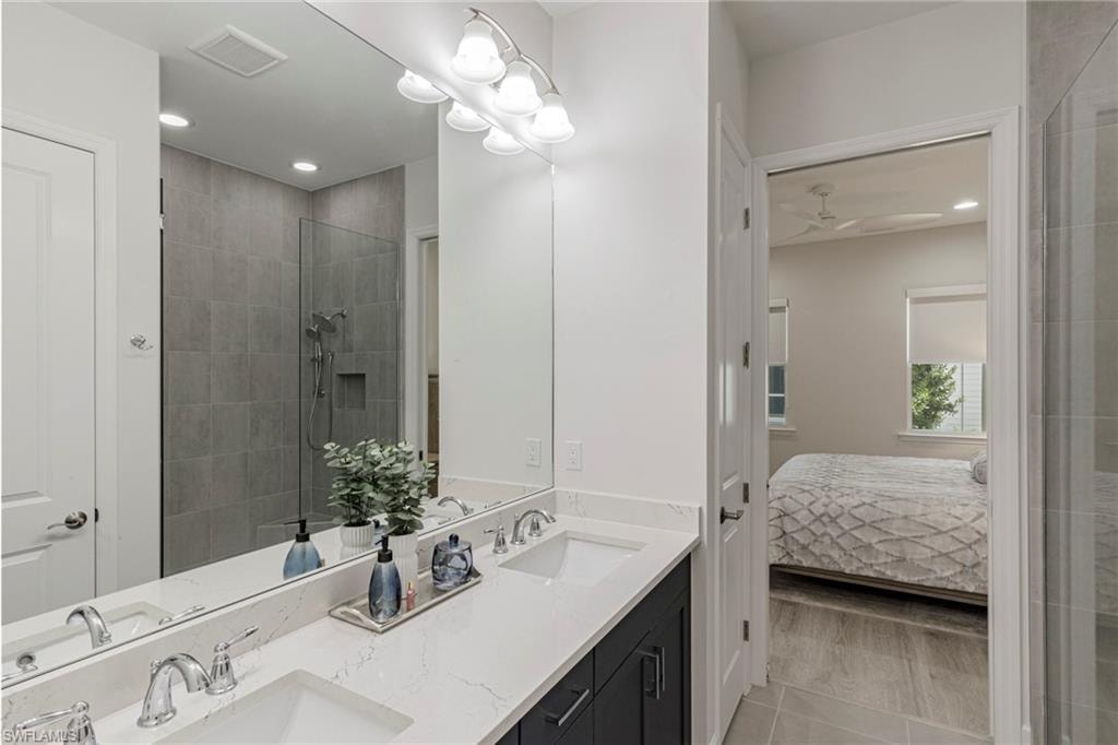 Bathroom featuring hardwood / wood-style flooring, double sink vanity, a shower with door, and ceiling fan
