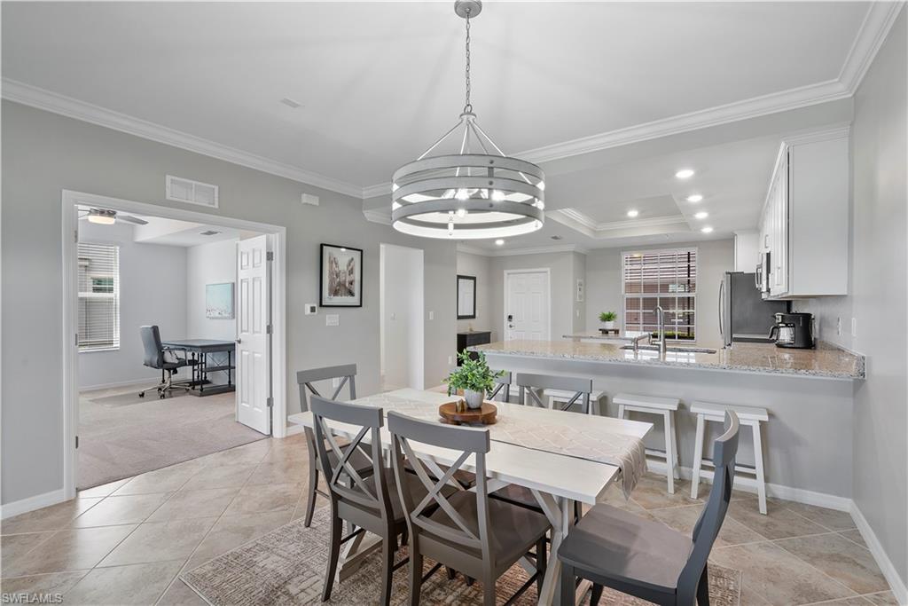 Dining room with a raised ceiling, ornamental molding, recessed lighting, an office area, and light tile patterned floors