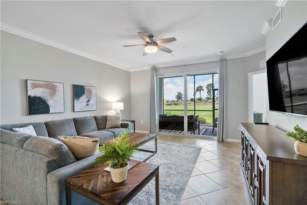 Living area featuring crown molding, light tile patterned flooring, and a ceiling fan